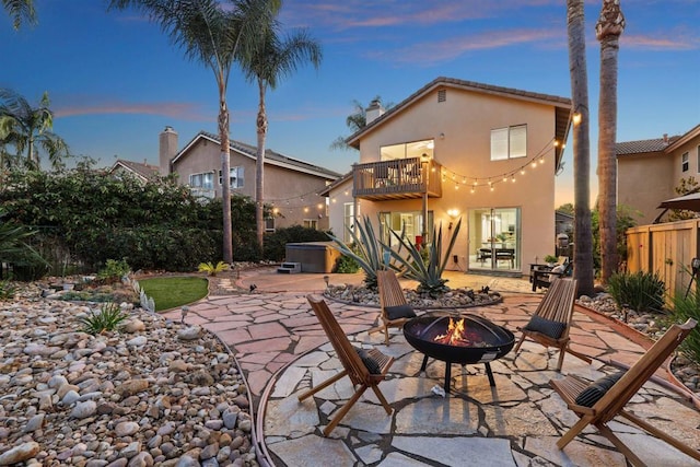 patio terrace at dusk featuring a balcony and a fire pit