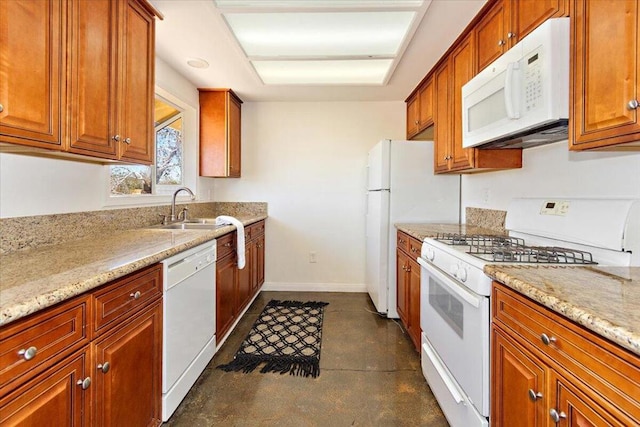 kitchen featuring white appliances, light stone counters, and sink