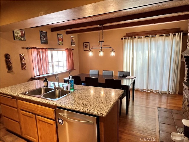 kitchen with an island with sink, sink, pendant lighting, stainless steel dishwasher, and beamed ceiling