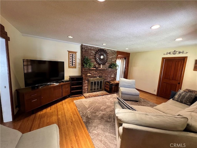 living room featuring a textured ceiling, a brick fireplace, and light hardwood / wood-style floors