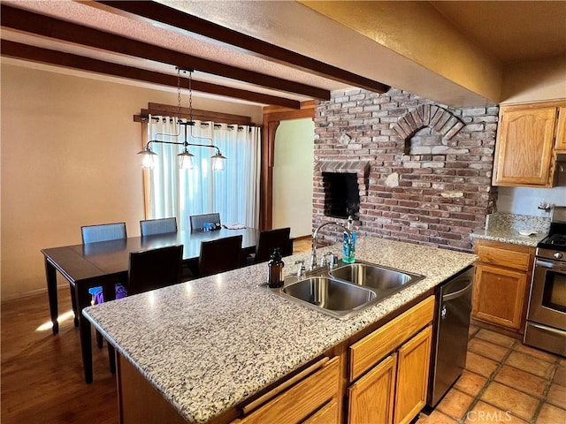 kitchen featuring a center island with sink, stainless steel appliances, sink, pendant lighting, and beamed ceiling