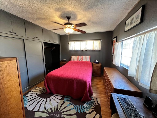 bedroom with ceiling fan, a textured ceiling, dark hardwood / wood-style floors, and a closet