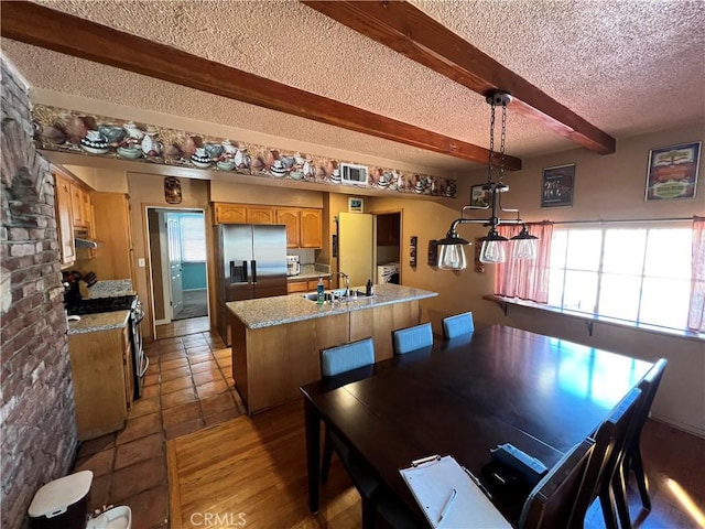 tiled dining room with a textured ceiling, sink, and beamed ceiling