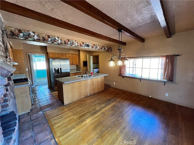 kitchen featuring stainless steel refrigerator with ice dispenser, a healthy amount of sunlight, hanging light fixtures, and sink