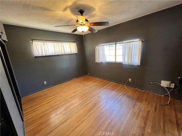 empty room featuring a textured ceiling, ceiling fan, and light hardwood / wood-style flooring