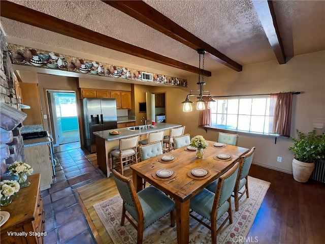 dining area featuring a textured ceiling, dark wood-type flooring, beam ceiling, and sink