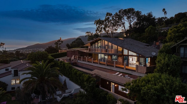 back house at dusk featuring a mountain view and a balcony