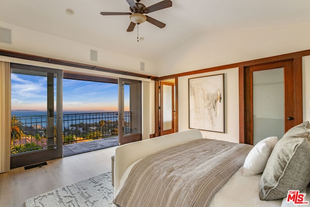 bedroom featuring light wood-type flooring, access to outside, vaulted ceiling, ceiling fan, and a water view