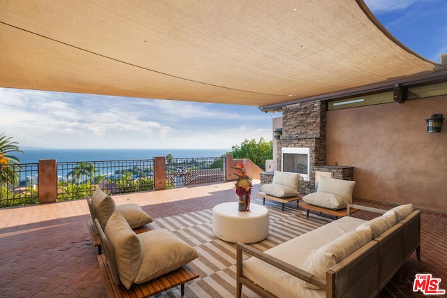 view of patio with an outdoor living space with a fireplace and a water view