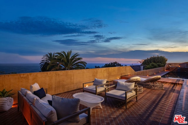 patio terrace at dusk with outdoor lounge area and a water view