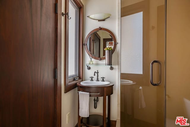 bathroom with a shower with door and sink