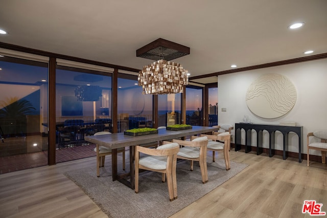 dining room featuring light wood-type flooring, crown molding, and a notable chandelier