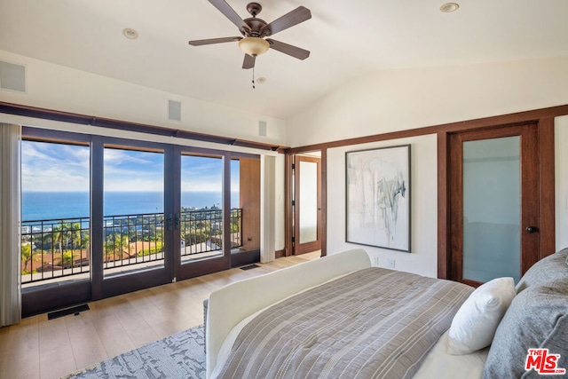 bedroom featuring multiple windows, a water view, vaulted ceiling, and light wood-type flooring