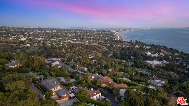 aerial view at dusk featuring a water view