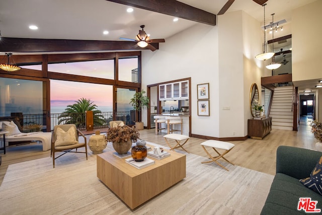 living room with ceiling fan, light hardwood / wood-style floors, beam ceiling, and a wealth of natural light