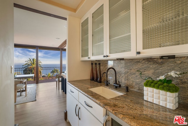 kitchen with floor to ceiling windows, white cabinets, sink, decorative backsplash, and stone countertops