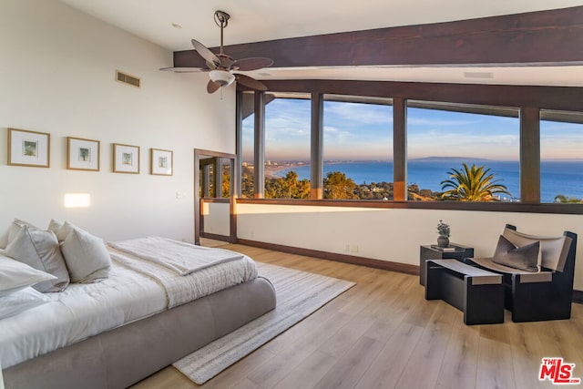 bedroom with lofted ceiling with beams, ceiling fan, a water view, and light hardwood / wood-style floors