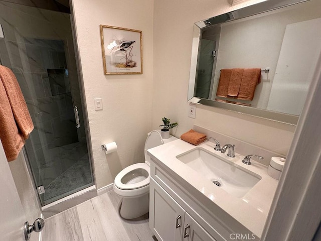 bathroom featuring vanity, a shower with shower door, toilet, and wood-type flooring