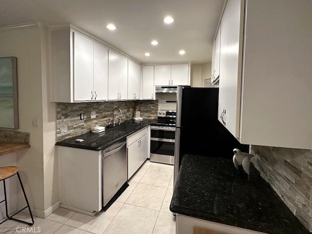 kitchen featuring white cabinets, appliances with stainless steel finishes, sink, backsplash, and light tile patterned floors