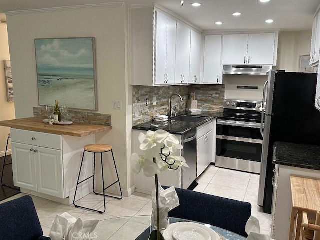 kitchen with light tile patterned floors, white cabinets, stainless steel appliances, and wood counters