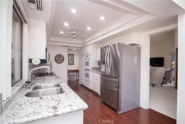 kitchen with a raised ceiling, sink, white cabinetry, and stainless steel refrigerator with ice dispenser