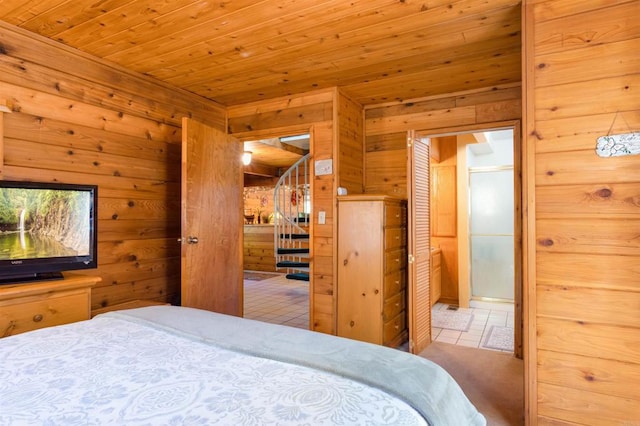 bedroom featuring ensuite bathroom, wooden ceiling, and wooden walls