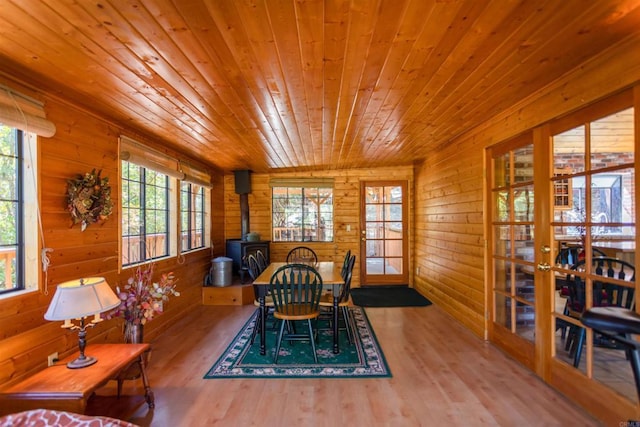 dining space with wood-type flooring, a wood stove, wooden walls, and wood ceiling