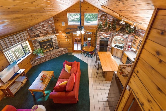 living room featuring tile patterned flooring, a fireplace, wooden walls, and plenty of natural light