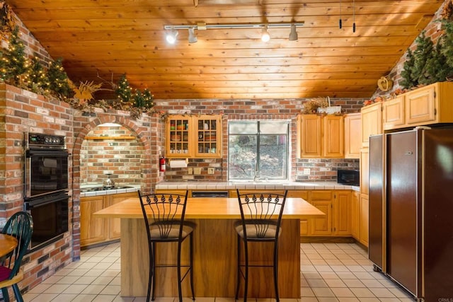 kitchen with a breakfast bar area, a center island, light tile patterned floors, black appliances, and wooden ceiling