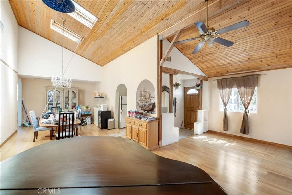 dining room with ceiling fan with notable chandelier, light hardwood / wood-style floors, high vaulted ceiling, and wooden ceiling