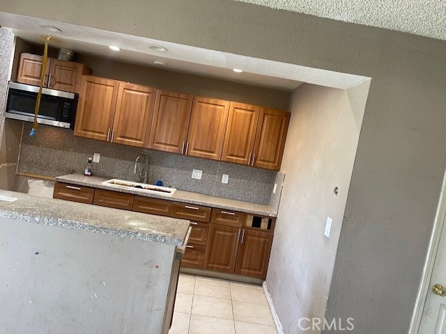 kitchen with light stone countertops, sink, light tile patterned flooring, and tasteful backsplash