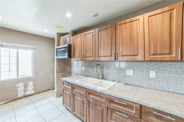 kitchen with light stone countertops, light tile patterned floors, decorative backsplash, and sink