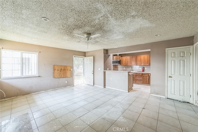 kitchen with a textured ceiling, light tile patterned floors, and ceiling fan