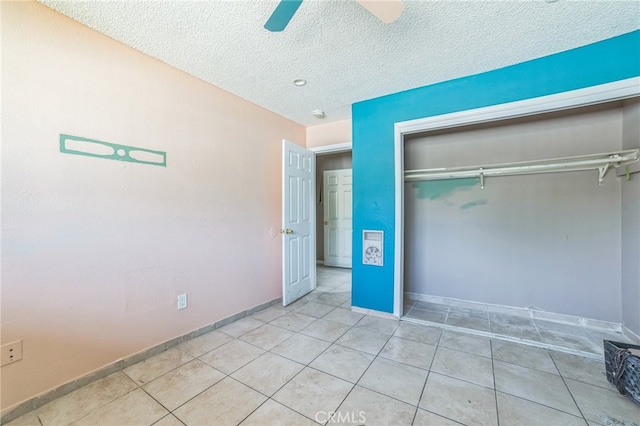 unfurnished bedroom featuring a closet, a textured ceiling, light tile patterned floors, and ceiling fan