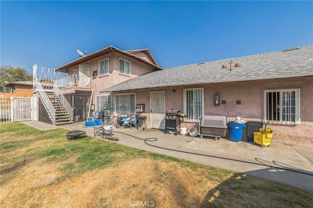 back of property featuring a yard, a patio, and a fire pit