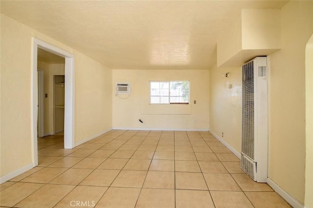 spare room with a textured ceiling, a wall mounted AC, light tile patterned floors, and a heating unit