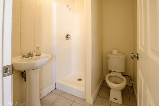 bathroom with a shower, sink, toilet, and tile patterned floors