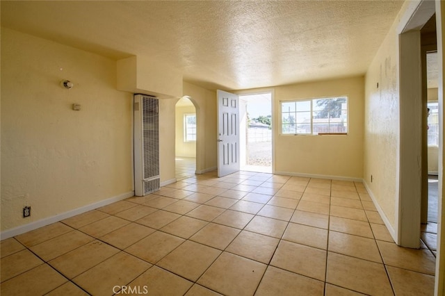 empty room with light tile patterned floors and a textured ceiling