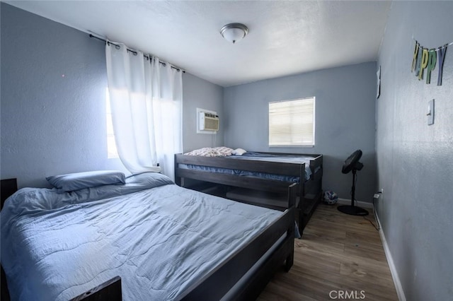 bedroom with dark hardwood / wood-style floors and a wall mounted AC