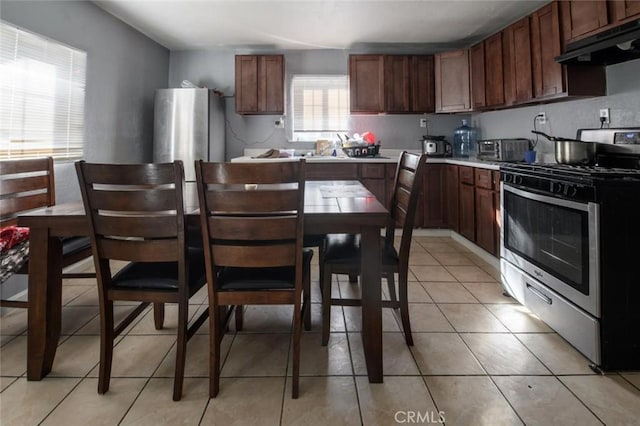 kitchen featuring under cabinet range hood, gas stove, light countertops, and light tile patterned floors