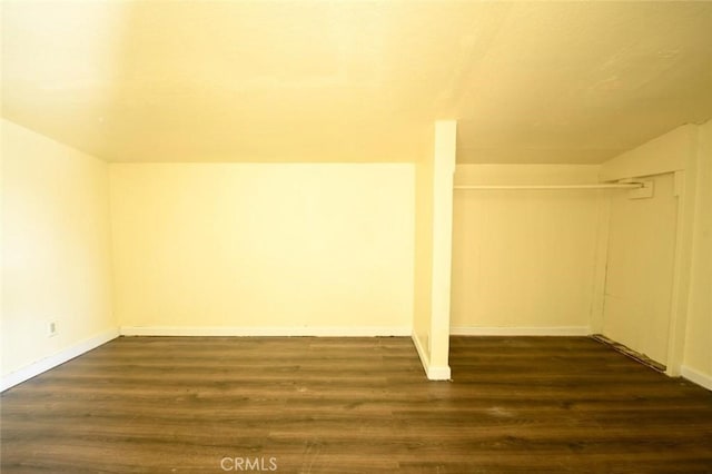 bonus room featuring dark wood-type flooring and baseboards