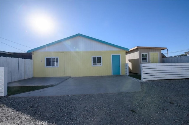 rear view of house featuring a patio area, fence private yard, and an outbuilding