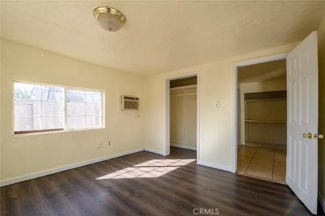 unfurnished bedroom with an AC wall unit, a textured ceiling, a closet, and dark hardwood / wood-style flooring