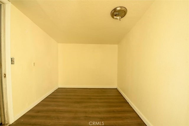 additional living space with dark wood-type flooring and baseboards