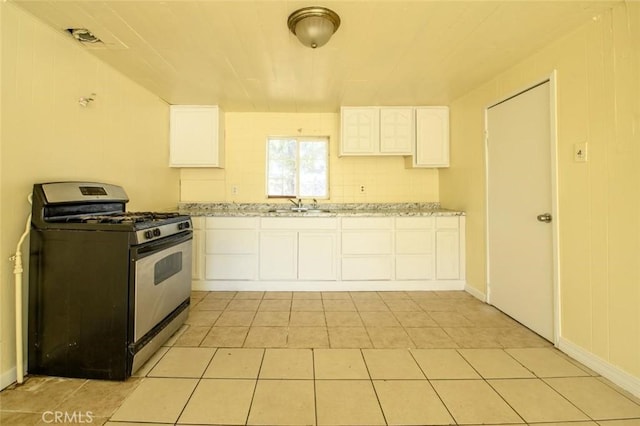 kitchen with a sink, white cabinetry, gas stove, and light tile patterned flooring