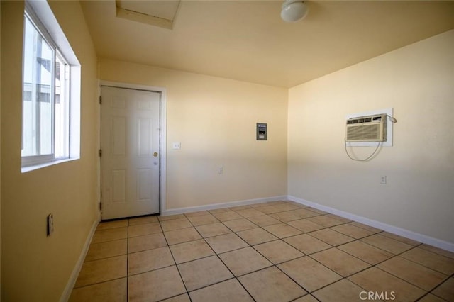 unfurnished room featuring light tile patterned floors, an AC wall unit, and baseboards