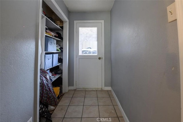 doorway featuring light tile patterned floors and baseboards