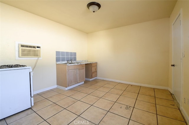 kitchen featuring light stone counters, a wall mounted air conditioner, sink, light tile patterned flooring, and white range