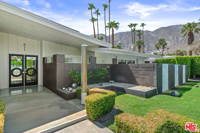 exterior space featuring french doors, a mountain view, a yard, and a patio area