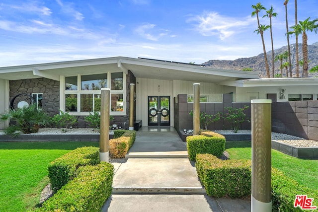 entrance to property with a mountain view and a lawn